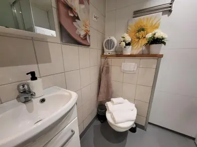 a bathroom with a sink and a toilet and flowers at Mars Modern and Cozy Apartment in the centre, Free Parking in Trondheim