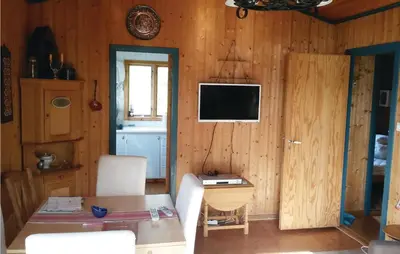 a living room with a table and a tv on a wall at Nice Home In Eikelandsosen With Sauna in Eikelandsosen
