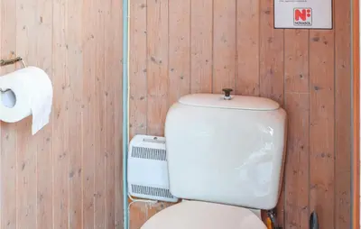 a bathroom with a toilet and a roll of toilet paper at Nice Home In Eikelandsosen With Sauna in Eikelandsosen