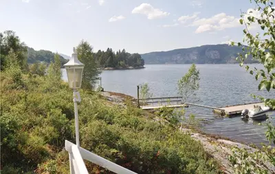 a street light next to a lake with a dock at Nice Home In Eikelandsosen With Sauna in Eikelandsosen