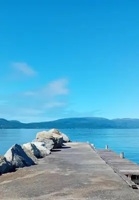 a dock in the water with rocks on it at Apartment by the fjord in Storekra