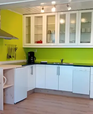 a kitchen with white cabinets and a green wall at Apartment by the fjord in Storekra