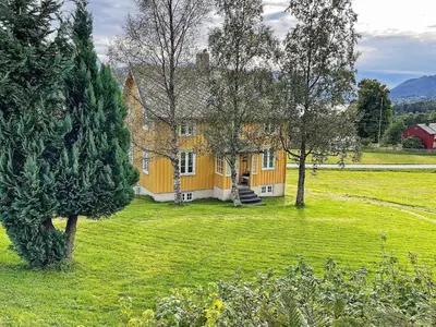 a large yellow house in a field with trees at 6 person holiday home in AVERØY-By Traum in Stein
