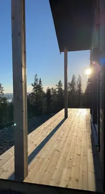 a wooden porch of a house with the sun in the background at Polaren by Norgesbooking - cabin with amazing view in Notodden