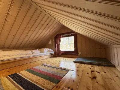 an attic room with a bed and a window at Cottage Yard - cozy Cabin in Geilo