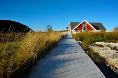 a pathway leading to a red house with tall grass at Atlantic Road Seaside Housing in Averoy