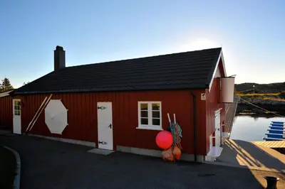 a red building with a house with a body of water at Atlantic Road Seaside Housing in Averoy