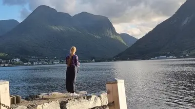a woman standing on a dock looking at a lake at Feriehus Voldstad in Syvde