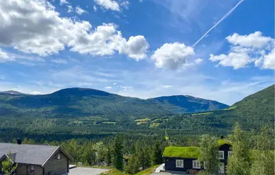 a house with a green roof with mountains in the background at Cozy Home In Bjorli With Wifi in Bjorli