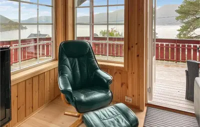 a green leather chair in a room with windows at 2 Bedroom Stunning Home In Foldfjorden in Skogli