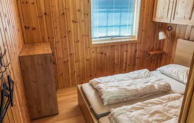two beds in a room with wooden walls and a window at 2 Bedroom Stunning Home In Foldfjorden in Skogli