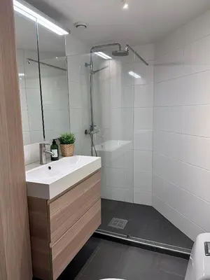 a white bathroom with a sink and a shower at Stunning penthouse in the city! in Ålesund