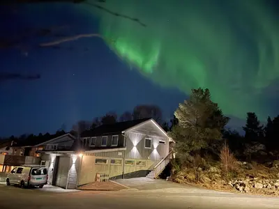 a house with a car parked in a parking lot under the aurora at Eksluzywny apartament w zaciszu in Kristiansund
