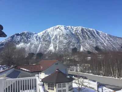 a snow covered mountain in front of a house at Sivert´s kontorhotell in Tomrefjord