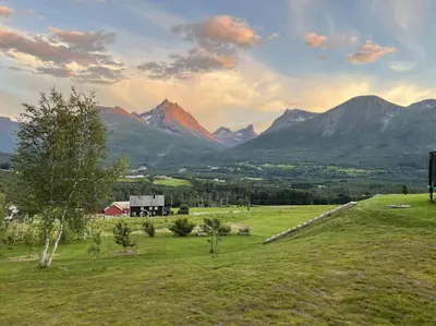a field with a barn and mountains in the background at Villa i Isfjorden! in Isfjorden