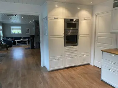 a kitchen with white cabinets and a living room at Villa i Isfjorden! in Isfjorden