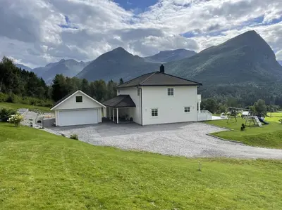 a large white house with mountains in the background at Villa i Isfjorden! in Isfjorden