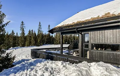 a building covered in snow next to a pile of snow at Cozy Home In Sjusjøen With Kitchen in Sjusjøen