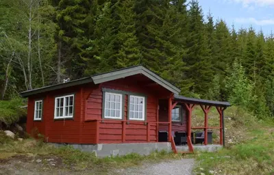 a red cabin in the middle of a forest at Hesthaug Gard in Eidsdal