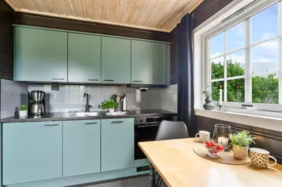 a kitchen with blue cabinets and a wooden table at Hygge Hütte - zwischen Fjell und Fjord in Lauvstad