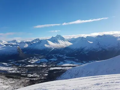 a view of a snow covered mountain range with a city at Kavli gjestehus - Isfjorden. in Isfjorden