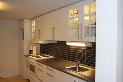 a kitchen with white cabinets and a sink at Kavli gjestehus - Isfjorden. in Isfjorden