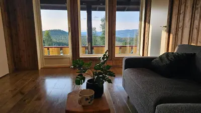 a living room with a couch and a table and windows at Huso Mountain Lodge - Hemsedal in Eikregardane