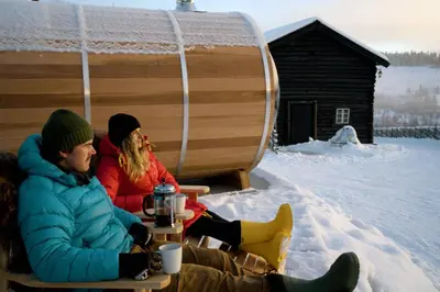 two people sitting in the snow in front of a igloo at Huso Mountain Lodge - Hemsedal in Eikregardane