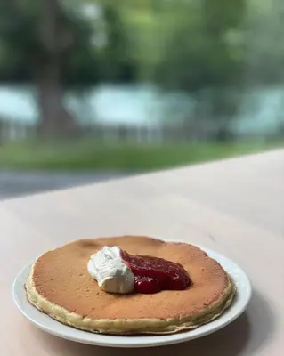 a pancake with jam and whipped cream on a plate at Nygård Camping in Hjelle