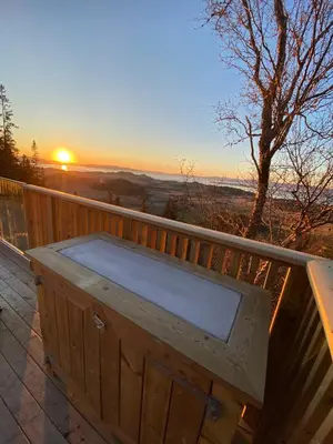 a hot tub on a deck with the sunset in the background at Forbord Dome in Tilleraune