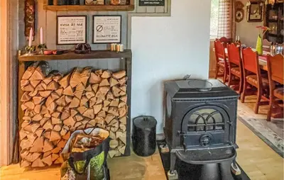 a stove in a room with a pile of wood at Cozy Home In Østby With Wifi in Trysil