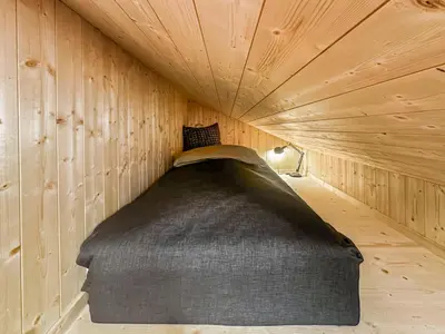 a bed in a wooden room with a ceiling at Ski-in-out hytte på Kvitfjell in Strande
