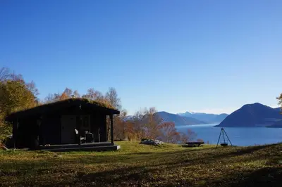 a small shack on a hill next to a body of water at Bregnehytte in Leikanger