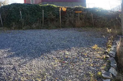 a gravel driveway with a fence and a house at Bregnehytte in Leikanger
