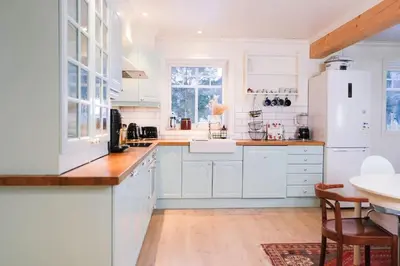 a kitchen with white cabinets and a table in it at Beautiful Private Villa with Lake View and Boat in Hålland