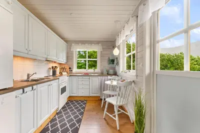 a kitchen with white cabinets and a table and chairs at Fjord Lodge direkt am Ufer des Dalsfjord in Lauvstad