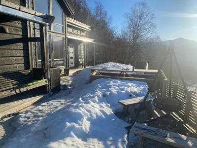 a snow covered porch of a house with the sun shining at Moderne hytte i Svandalen, Sauda - nær skisenter og natur in Sauda