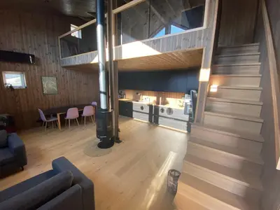 a living room with a staircase and a kitchen at Moderne hytte i Svandalen, Sauda - nær skisenter og natur in Sauda