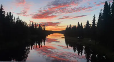 a view of a river with trees and a sunset at Hytte med Anneks og fantastisk utsikt på Ljøsheim in Mesnali