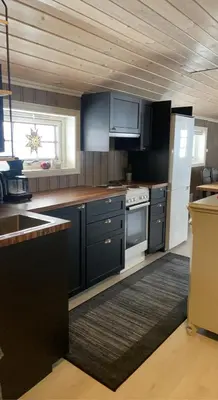 a kitchen with black cabinets and a white refrigerator at Hytte med Anneks og fantastisk utsikt på Ljøsheim in Mesnali