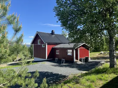 a red barn with a driveway in a field at Apartment Grønlid in Rauland