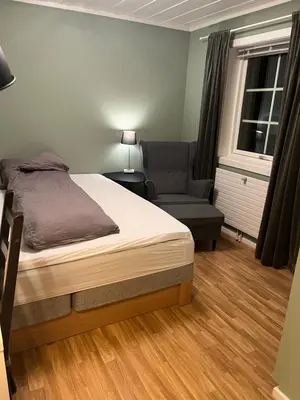 a bedroom with a bed and a chair and a window at Koselig rom i rolige omgivelser in Rena