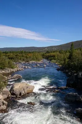 a river with rapids and rocks in a field at Stay in the heart of Geilo, walk to everything in Geilo