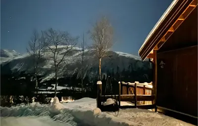 a snow covered house with a mountain in the background at Awesome Home In Hornindal With Wifi in Hornindal