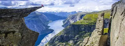 a person standing on the edge of a cliff overlooking a river at Odda Living - 3BR & 1BR - A3 in Tokheim
