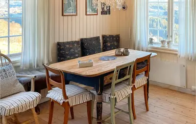 a wooden table in a room with chairs and windows at 4 Bedroom Cozy Home In Svorkmo in Brattli