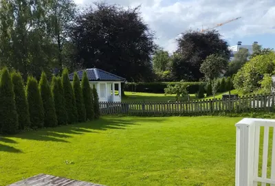 a yard with a fence and a white house at Førde sentrum - Lindbøen Gjesterom in Førde