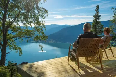 a man and a child sitting on a bench overlooking a lake at Sørheim FjordPanorama in Skjolden