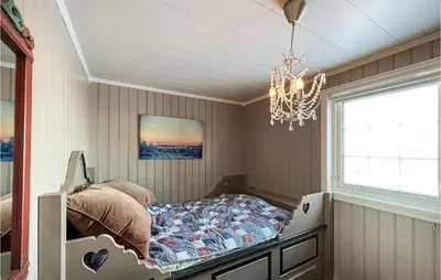 a bedroom with a bed in a room with a chandelier at 5 Bedroom Awesome Home In Røn in Ron