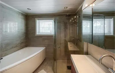 a bathroom with a tub and a shower and a sink at 5 Bedroom Awesome Home In Røn in Ron